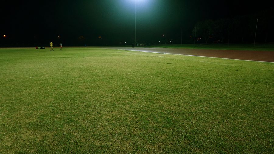 A field under a single stadium light at night