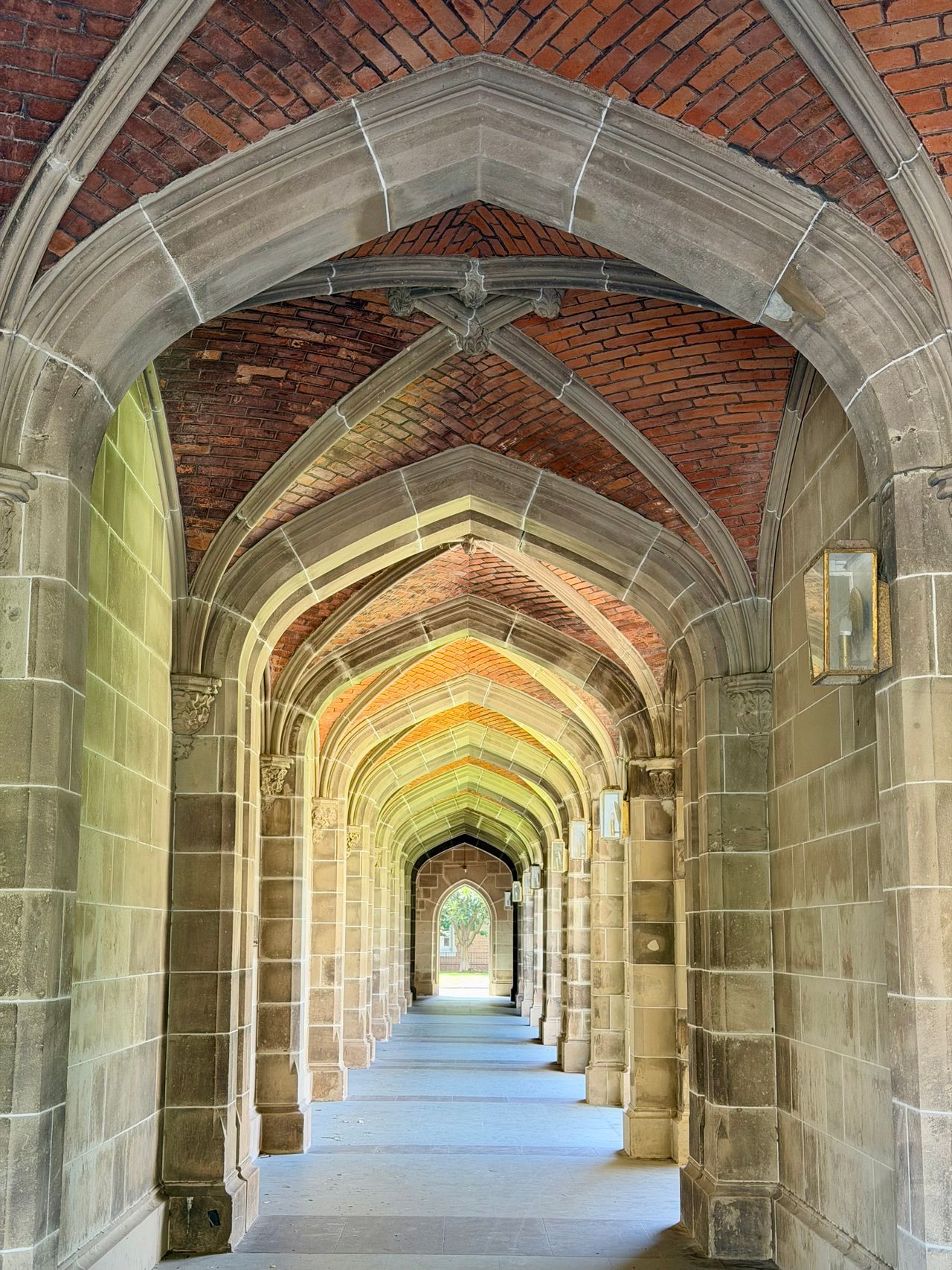 Gothic stone-and-brick cloister archways receding down a campus walkway