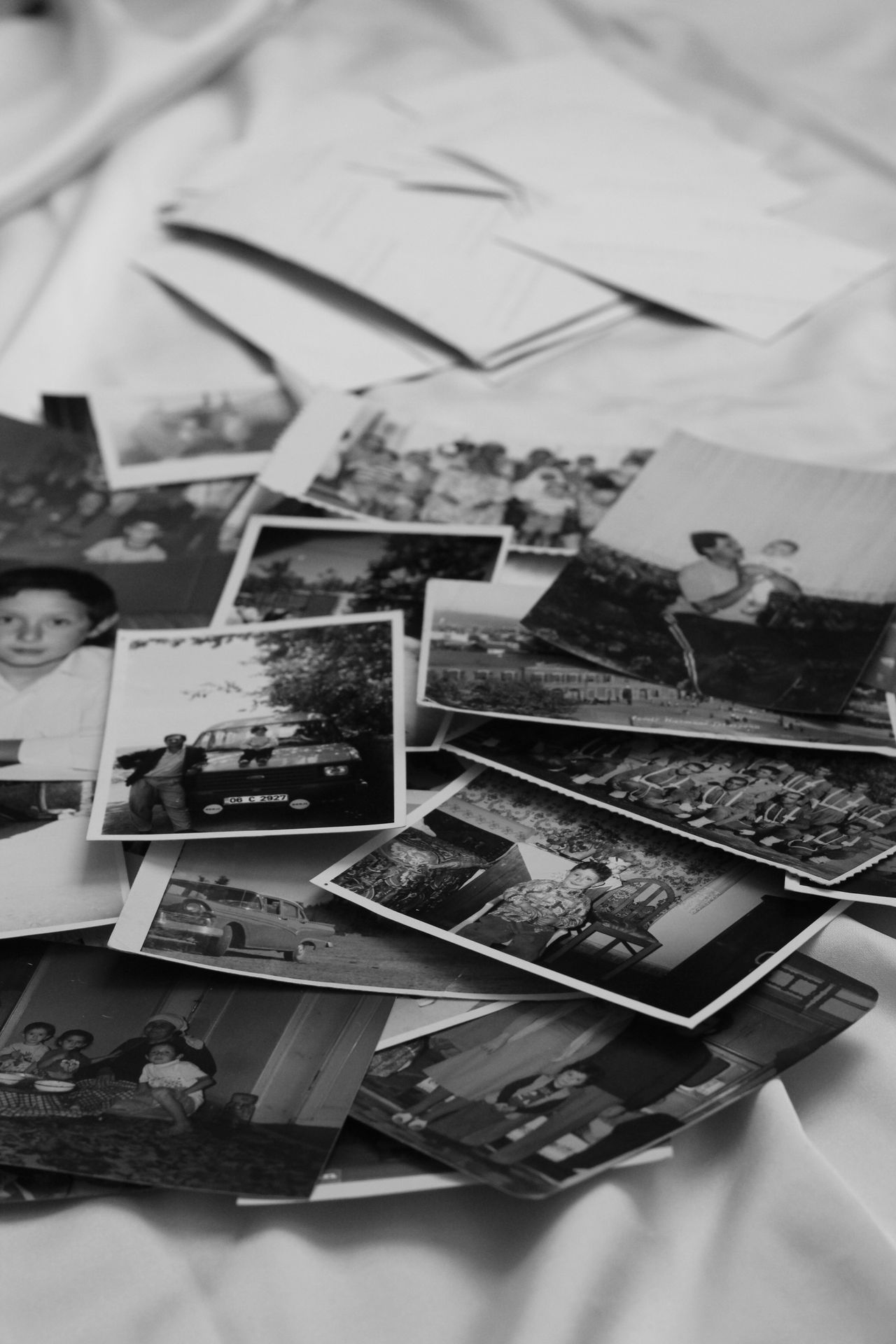 A scattered stack of old black-and-white photographs on a table